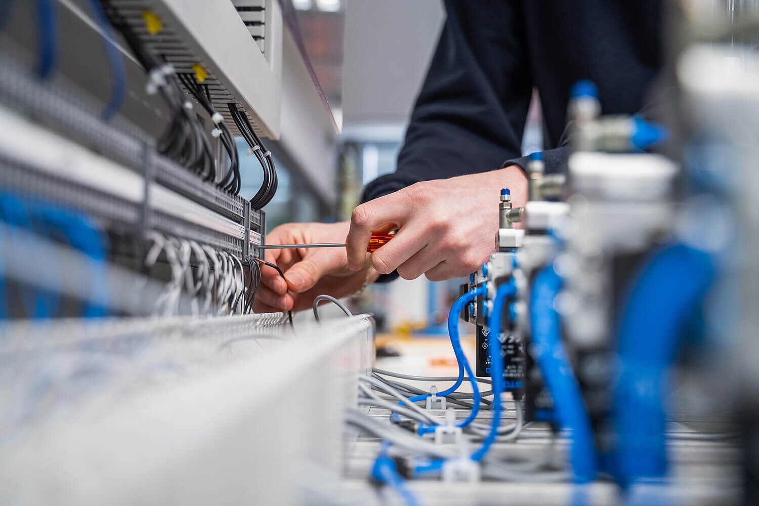 Elektrotableau mit Kabel und Händen, die Kabel anschliessen