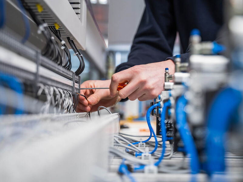 Elektrotableau mit Kabel und Händen, die Kabel anschliessen