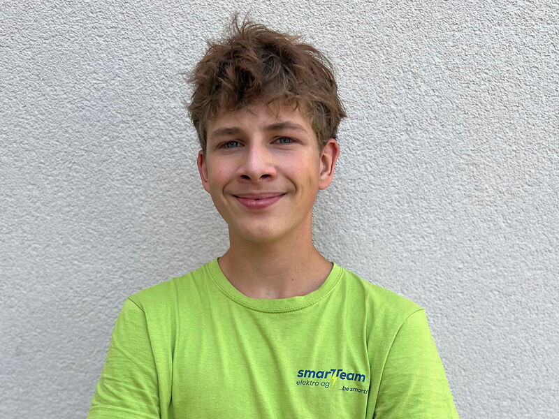 Junger Mann mit grünem T-Shirt, kurzen Haaren vor Mörtelwand